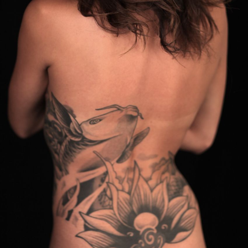 Tatouage carpe koï noir et blanc dans le dos d'une femme