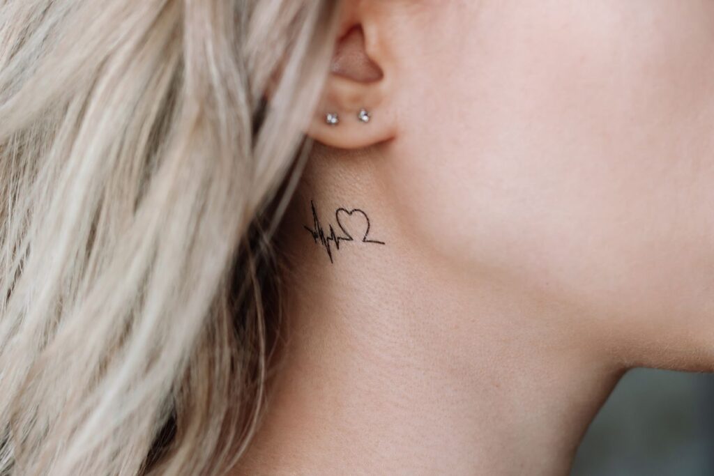 Petit tatouage coeur battement derrière l'oreille