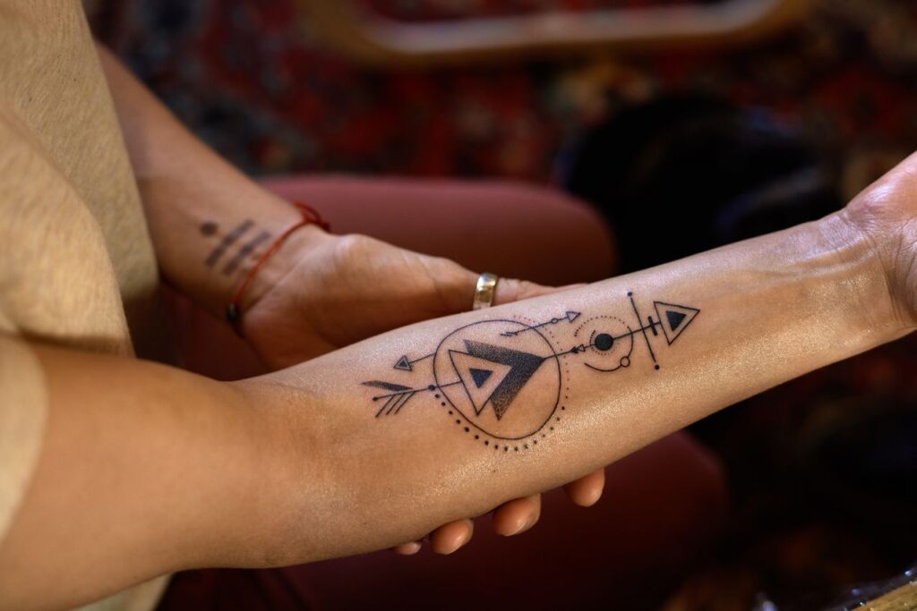 Tatouage d'une flèche avec plusieurs triangles sur le bras d'une femme