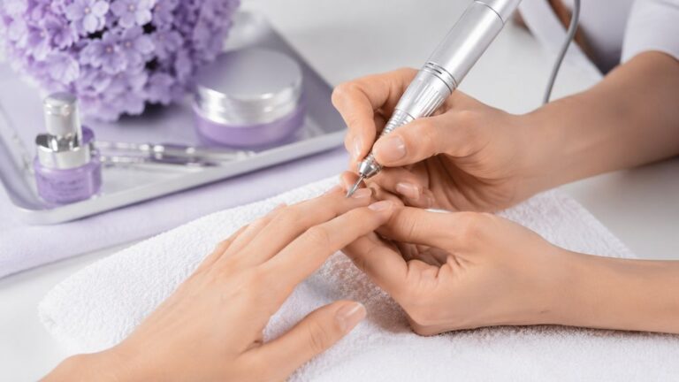 Prothésiste ongulaire utilisant une ponceuse électrique à ongles avec embout diamant sur une cliente en salon professionnel